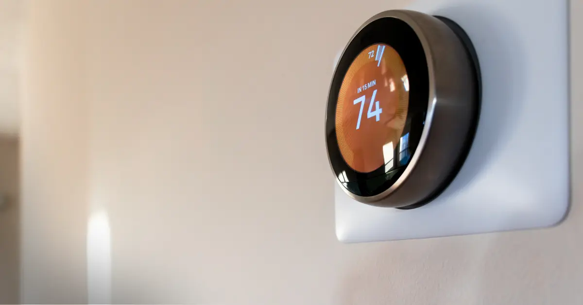 Smart thermostat on a wall displaying the temperature of 74°F
