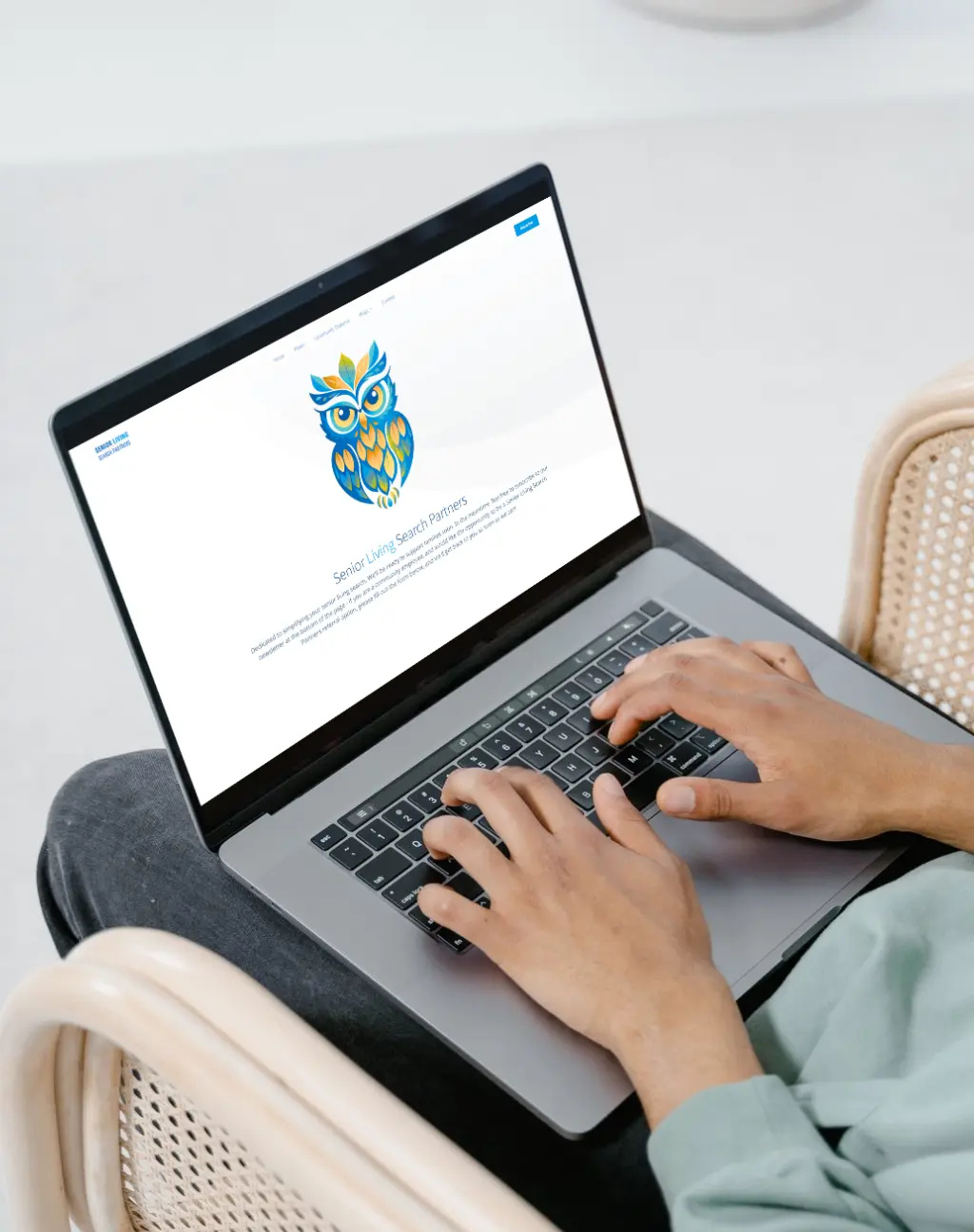 A person using a laptop with the Senior Living Search Partners website open, featuring a colorful owl logo on a clean design.
